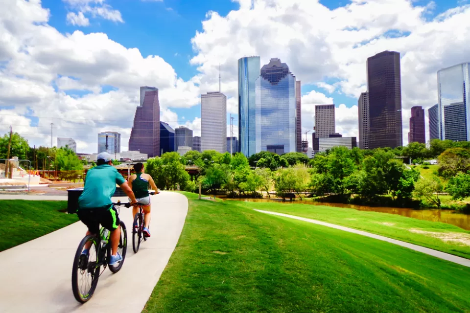 Two people on a bike trail with downtown Houston in the background